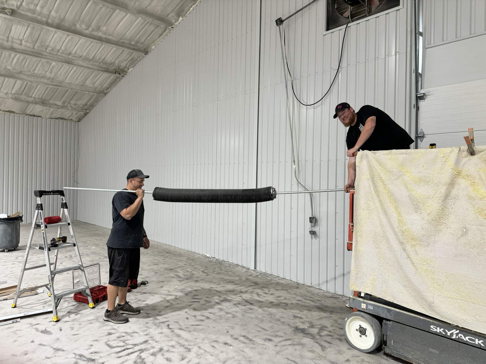 Garage Door Technicians Working On Installing Springs for a Commercial Garage Door